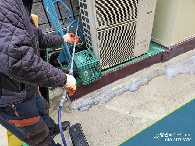 실외기 옆에서 호스로 배관을 세척하는 중