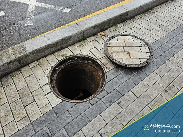 보도에서 뚜껑을 연 원형 맨홀